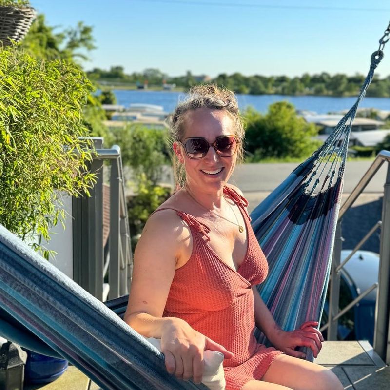 Lisa Sofie Zelgin sitzt mit Sonnenbrille in einer Hängematte, dahinter ein See