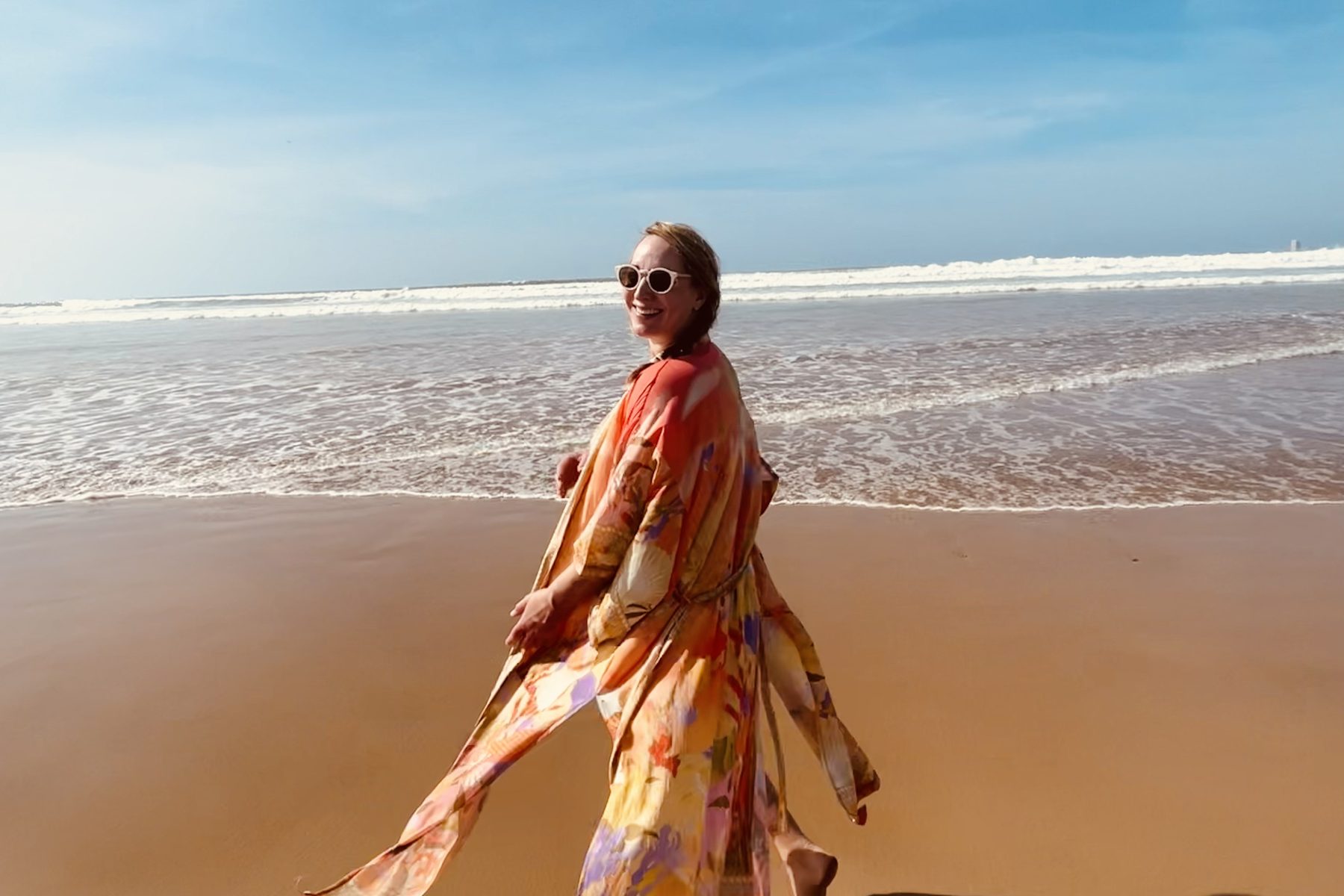 Lisa Sofie Zelgin geht am Strand entlang, das Kleid weht im Wind, dahinter das Meer